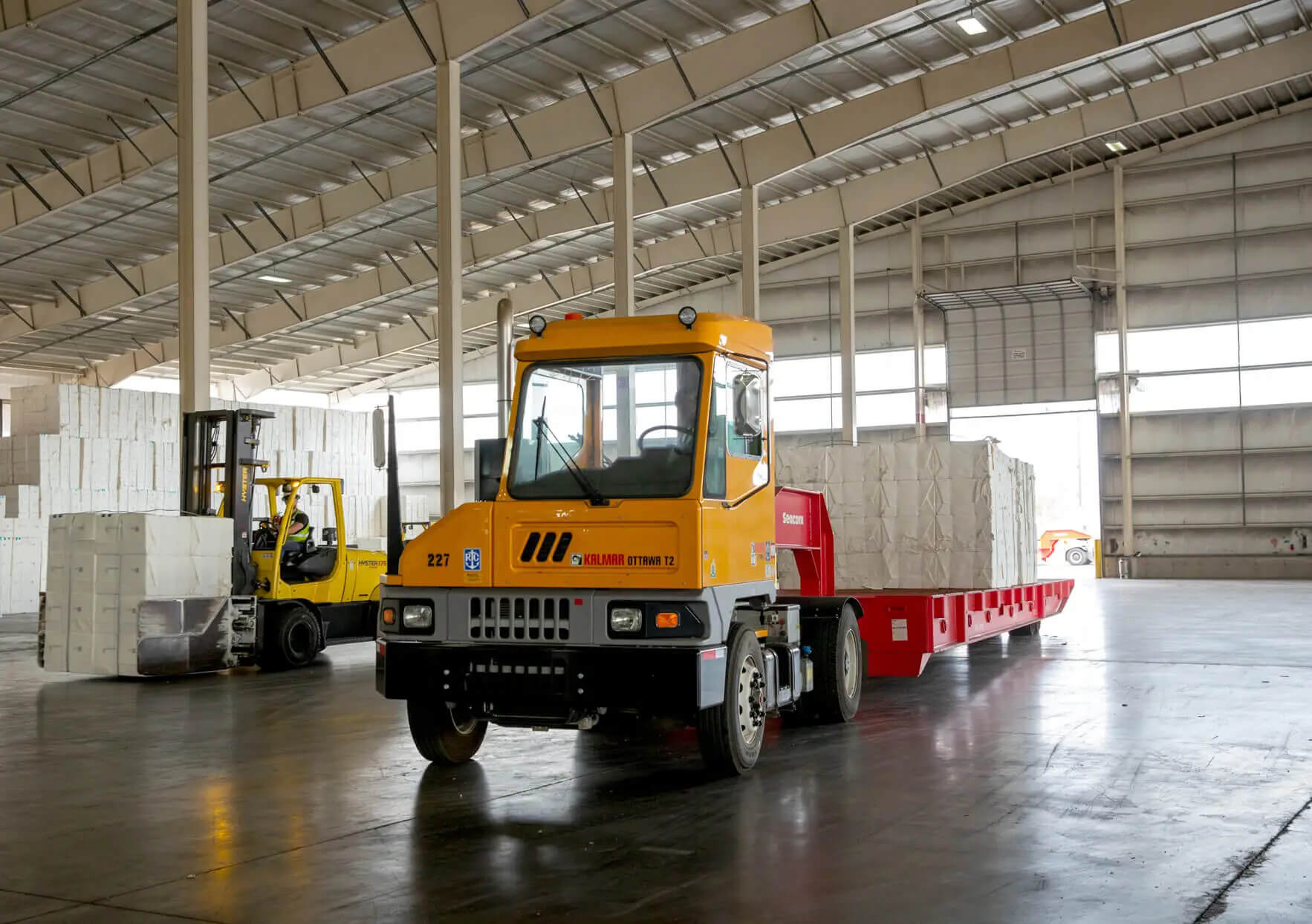 kalmar tractor pulling trailer loaded with paper in warehouse
